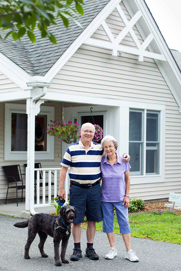 two residents in front of their townhome with dog